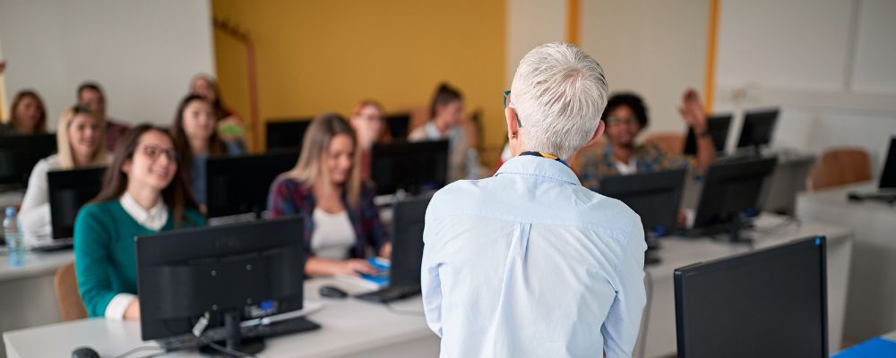 Profesor imparte una clase ante un grupo de alumnos en un aula informática.