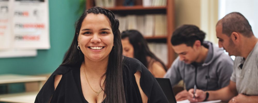 Estudiantes siguen una clase en un aula con ordenadores.